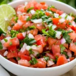 Bowl Of Fresh Pico De Gallo With Diced Tomatoes, Onions, And Cilantro Garnished With Lime On A Wooden Table.