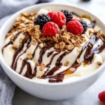 Frozen Cottage Cheese Dessert In A White Bowl, Swirled With Chocolate And Topped With Granola And Fresh Berries