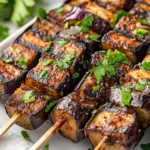 Grilled Eggplant Skewers With Honey Tahini Arranged On A White Plate, Garnished With Parsley And Colorful Bell Peppers