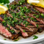 Grilled Flank Steak With Chimichurri On A White Plate, Garnished With Parsley And A Lemon Wedge
