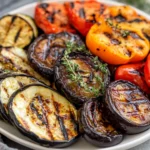 Grilled Vegetable Platter Featuring Eggplant, Zucchini, And Peppers, Garnished With Fresh Thyme On A White Plate.