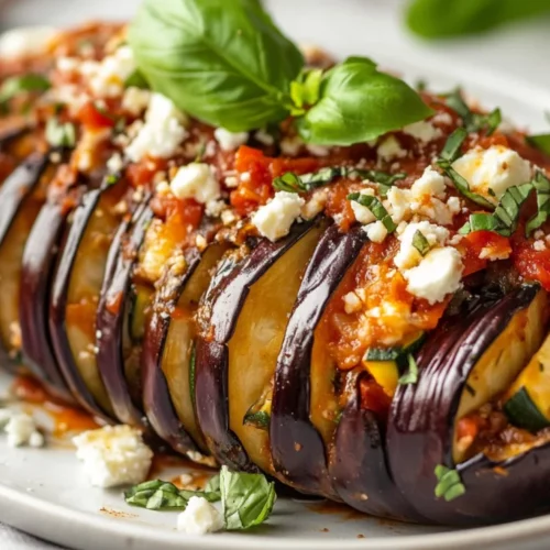 Hasselback Eggplant With Greek Flavors - Healthy &Amp; Delicious 2 Hasselback Eggplant Topped With Melted Cheese And Fresh Herbs On A White Plate, Garnished With Marinara Sauce