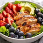 Healthy Berry Salad Bowl With Mixed Greens, Strawberries, Avocado, And Chicken In A White Bowl