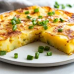 How To Make Spanish Tortilla Served On A White Plate, Garnished With Green Onions And Sprinkled With Salt
