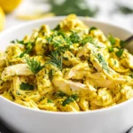 Lemon Turmeric Chicken Salad In A White Bowl, Garnished With Fresh Dill And Lemon Zest