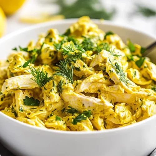Lemon Turmeric Chicken Salad In A White Bowl, Garnished With Fresh Dill And Lemon Zest