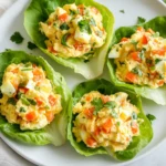 Light Egg Salad Lettuce Wraps On A White Plate, Filled With Veggies And Garnished With Fresh Herbs.