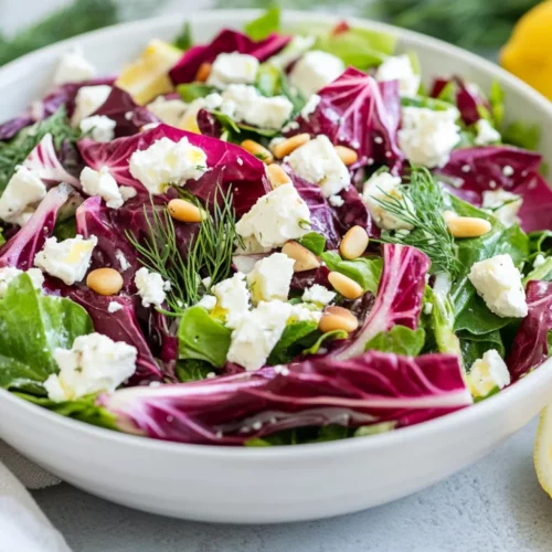 Fresh Maroulosalata Salad In A White Bowl With Feta, Pine Nuts, And Dill, Garnished With Lemon Wedges