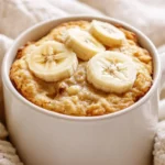 Warm Microwave Banana Bread Mug Topped With Banana Slices On A White Background