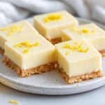 No Bake Vegan Lemon Bars On A White Plate, Garnished With Lemon Zest And A Tidy Edge, Showcasing A Creamy Texture.