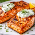 Pan-Seared Salmon With Dill Sauce On A White Plate Garnished With Fresh Dill And A Lemon Slice