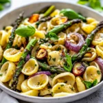 Pasta Salad With Roasted Garlic Vinaigrette Served In A White Bowl, Topped With Fresh Basil And Roasted Vegetables