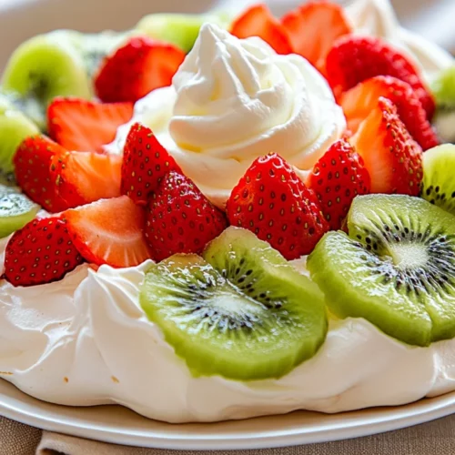 Pavlova Dessert Topped With Fresh Strawberries And Kiwis On A White Plate With Whipped Cream