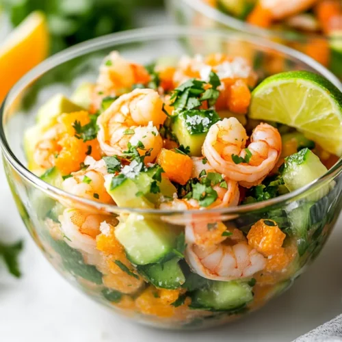 The Ultimate Shrimp Ceviche Recipe For Healthy Eats 2 Vibrant Shrimp Ceviche In A Glass Bowl With Avocado, Cucumber, And Lime Wedges On A White Surface