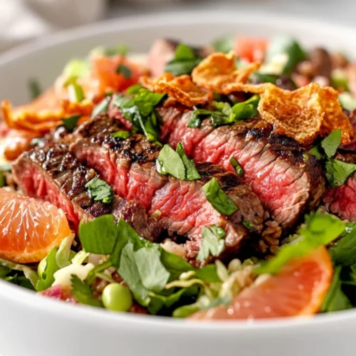 Steak Grapefruit Salad: A Protein-Packed, Healthy Recipe Idea 2 Steak Grapefruit Salad In A White Bowl, Topped With Fresh Herbs And Crispy Onions, Against A Neutral Background.