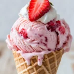 Delicious Strawberry Cheesecake Ice Cream In A Waffle Cone Topped With Whipped Cream And Fresh Strawberries