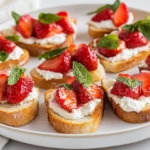 Healthy Strawberry Crostini On A White Plate, Topped With Ricotta, Strawberries, And Mint Leaves
