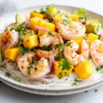 Thai Prawn Mango Avocado Salad On A White Plate, Garnished With Fresh Cilantro And Red Onion