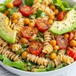 Vibrant Vegan Caesar Pasta Salad In A White Bowl, Topped With Avocado Slices And Roasted Chickpeas