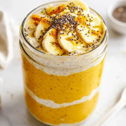 Vegan Overnight Oats With Turmeric: A Golden Breakfast Delight 2 Vegan Overnight Oats With Turmeric In A Glass Jar, Topped With Banana And Chia Seeds, On A White Background.