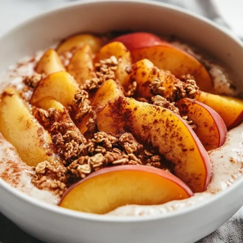 Warm Peach Yogurt Bowl With Caramelized Peaches And Granola In A White Bowl On A Neutral Surface
