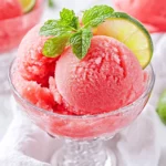 Bowl Of Watermelon Mojito Sorbet Garnished With Fresh Mint And Lime Slice On A White Surface