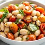 White Bean Caprese Salad In A White Bowl Topped With Fresh Basil And Drizzled With Balsamic Glaze